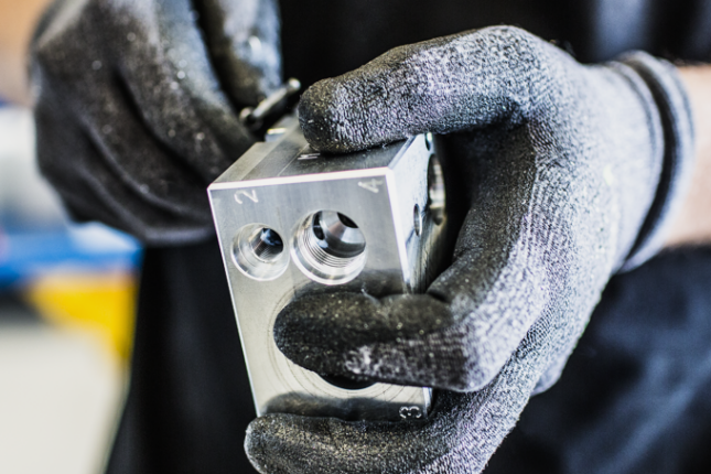 Hydraulblock i aluminium h&aring;lls av tekniker &ndash; precision och kvalitet i fokus.